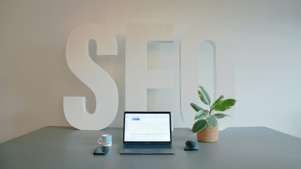 Laptop on a desk with a large SEO sign in the background