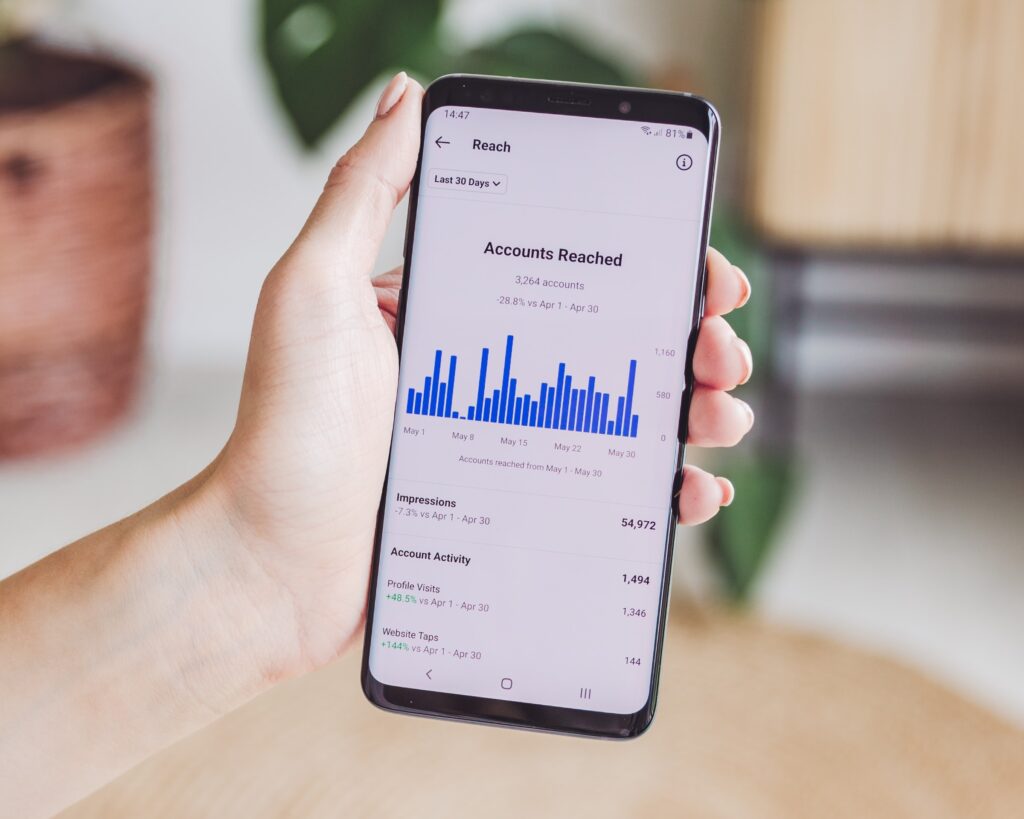 Hand holding a phone showing Instagram reach and engagement analytics